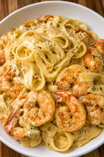 Creamy garlic shrimp Alfredo pasta made with tender fettuccine, juicy sautéed shrimp, and a rich Parmesan cream sauce, served in a white bowl for a comforting seafood dinner.