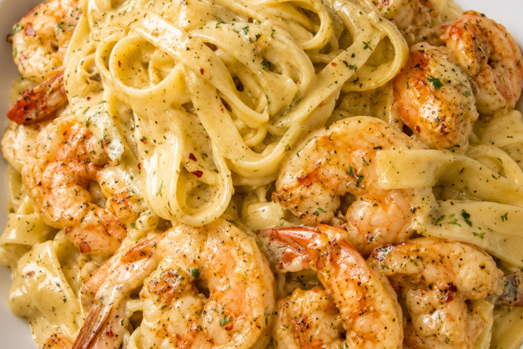 Creamy garlic shrimp Alfredo pasta made with tender fettuccine, juicy sautéed shrimp, and a rich Parmesan cream sauce, served in a white bowl for a comforting seafood dinner.