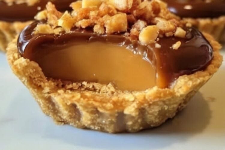 Name Mini Butterfinger Caramel Chocolate Pies Summary Buttery graham cracker crusts filled with caramel cream, topped with glossy chocolate and crunchy Butterfinger pieces. These easy no-bake desserts taste like your favorite childhood candy bars and are perfect for holiday party desserts and make-ahead sweets. Equipment Muffin tin (or cupcake liners) Mixing bowls Electric mixer or whisk Spoon for layering Ingredients Crust: 1½ cups graham cracker crumbs 6 tablespoons unsalted butter, melted ½ cup granulated sugar Filling & Topping: 1 cup thick caramel sauce 1 cup heavy cream, chilled 1 tablespoon powdered sugar ¾ cup melted chocolate 4 Butterfinger candy bars, crushed Instructions Preheat oven to 350°F and prepare muffin tin. Mix graham crumbs, melted butter, and sugar. Press into muffin cups. Bake crusts 8–10 minutes. Cool completely. Whip heavy cream and powdered sugar to soft peaks. Fold in half the caramel. Spoon caramel cream into crusts. Drizzle remaining caramel on top. Add thin layer of melted chocolate. Sprinkle crushed Butterfinger while chocolate is soft. Chill at least 2 hours until set. Notes Prep Time: 20 minutes | Chill Time: 2+ hours | Total Time: ~2.5 hours Yield: 12 mini pies Make-ahead: Prepare up to 2 days in advance and keep refrigerated. Storage: Store in an airtight container in the fridge for up to 4 days. Pro Tip: Use thick caramel sauce to prevent leaking. Crush Butterfingers finely for even topping. Variations: Swap Butterfinger for Reese’s, Snickers, or your favorite candy bar. Perfect for: Easy no-bake desserts, holiday party desserts, birthday treats, and crowd-pleasing make-ahead sweets.