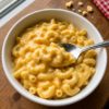 Creamy KFC-style Mac and Cheese made with tender elbow macaroni coated in a rich, velvety blend of melted Velveeta and sharp cheddar cheese. This smooth, cheesy comfort food side dish is served hot in a bowl with a creamy, glossy sauce that's perfect alongside fried chicken, barbecue, or family dinners.