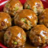 French onion meatballs baked in a glossy savory sauce with green onions and rice, served hot with extra sauce spooned over the top for a cozy family dinner.