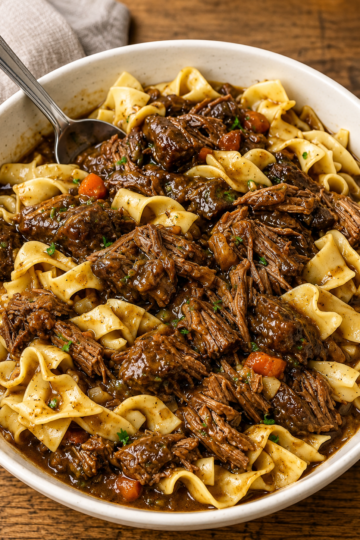 A comforting bowl of Crockpot Beef and Noodles made with tender slow-cooked chuck roast, soft egg noodles, and a rich, savory beef gravy, garnished with fresh parsley. This hearty slow cooker dinner is warm, flavorful, and perfect for cozy family meals, busy weeknights, or comforting Sunday suppers.