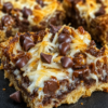Magic coconut caramel bars cut into squares with buttery graham cracker crust, toasted coconut, melted chocolate chips, chopped nuts, and gooey caramel filling.