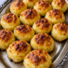 Golden Appalachian Cheesy Potato Puffs baked until crispy with a buttery Parmesan crust and fluffy mashed potato center loaded with sharp cheddar cheese and garlic. These old-fashioned homemade potato puffs are served warm on a rustic platter, making the perfect comfort food side dish for family dinners, holidays, and potlucks