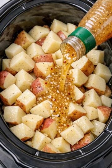 Slow Cooker Italian Herb Potatoes made with tender red or yellow potatoes coated in zesty Italian salad dressing and herbs. The potatoes are cooked until fork-tender while still holding their shape, then served warm with flavorful dressing and herbs coating each piece. A simple, rustic side dish perfect for a comforting family dinner.