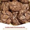 A stack of fudgy brownie mix cookies with shiny, crackly tops, soft chocolate centers, and slightly crisp edges. One cookie is broken in half to reveal the rich, gooey interior with melted chocolate throughout. Arranged on a cooling rack with scattered chocolate chips on a rustic wooden table, photographed in warm natural light for a cozy homemade dessert presentation.