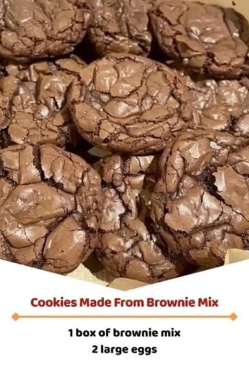 A stack of fudgy brownie mix cookies with shiny, crackly tops, soft chocolate centers, and slightly crisp edges. One cookie is broken in half to reveal the rich, gooey interior with melted chocolate throughout. Arranged on a cooling rack with scattered chocolate chips on a rustic wooden table, photographed in warm natural light for a cozy homemade dessert presentation.