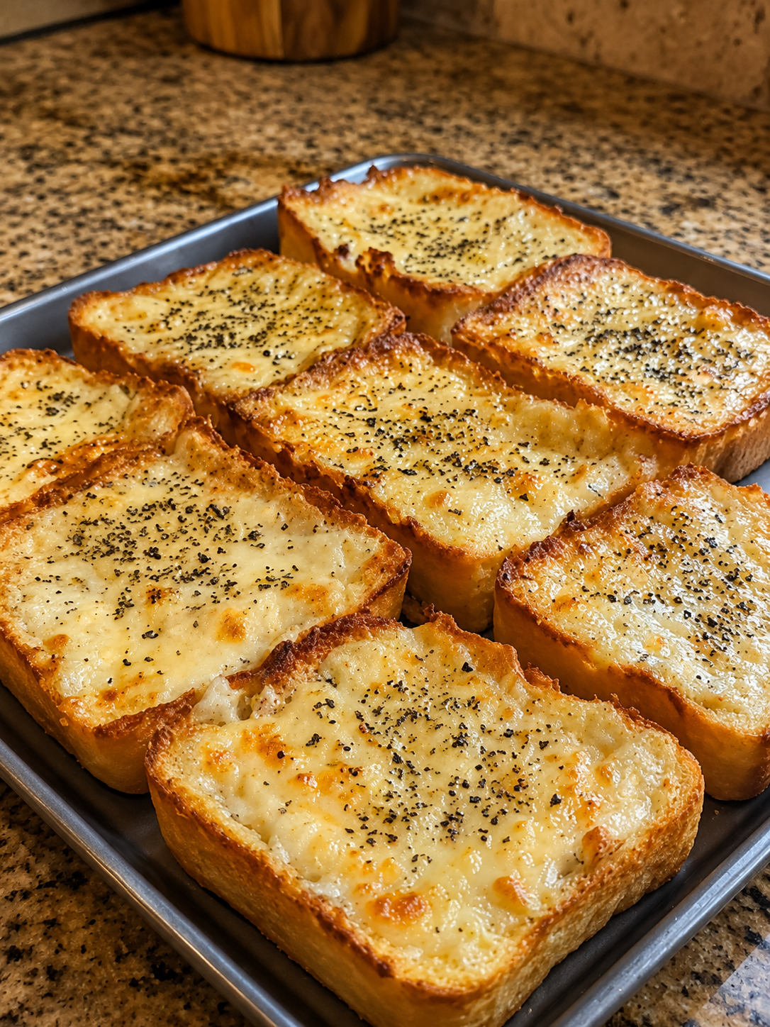 Close-up of cheesy garlic Texas toast made with thick slices of buttery bread, topped with melted mozzarella, provolone, and Parmesan cheese. The toast is baked until golden and bubbly with crispy edges, then sprinkled with dried parsley and served on a rustic wooden board in warm natural light. Long, gooey cheese pulls and a rich garlic butter topping create an irresistible homemade side dish.