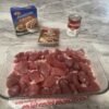 A comforting plate of tender beef tips coated in rich brown gravy, served over creamy mashed potatoes with a side of vegetables.