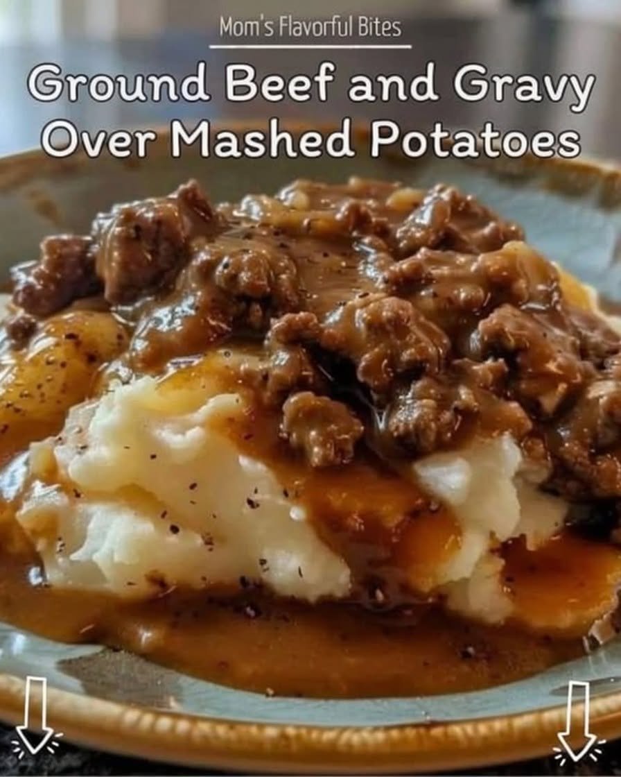 A comforting plate of creamy mashed potatoes topped with rich, savory ground beef gravy, featuring tender onions and a glossy peppery sauce, served hot in a bowl.