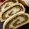 Hungarian nut rolls sliced open to reveal a sweet walnut-cinnamon filling inside soft, golden pastry, lightly glazed with icing.