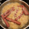Tangy sauerkraut simmered in butter with plump hot dogs until everything is soft, savory, and deeply comforting. A classic low-effort Sunday dinner.