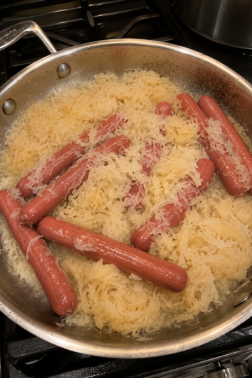 Tangy sauerkraut simmered in butter with plump hot dogs until everything is soft, savory, and deeply comforting. A classic low-effort Sunday dinner.