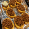 Open-faced Texas Toast Sloppy Joes made with thick slices of buttery golden Texas toast topped with a rich, savory ground beef and onion mixture in a tangy tomato sauce. Finished with melted shredded cheddar cheese and served on a rustic wooden board with pickles and crispy fries. Photographed in warm natural light, showcasing the crisp toast, juicy beef, and gooey cheese for a comforting homemade family dinner.