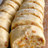 Alt text: Butterscotch shortbread cookies sliced from a log, showing a tender, buttery interior filled with golden butterscotch and toffee bits, lightly dusted with powdered sugar.