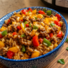 A colorful Beef and Pepper Rice Bowl made with seasoned ground beef, fluffy white rice, sautéed red and green bell peppers, and tender onions, all tossed in a savory soy and hoisin sauce. Garnished with freshly sliced green onions and served in a rustic bowl on a wooden table in warm natural light, creating a quick, hearty, takeout-style meal perfect for busy weeknights.