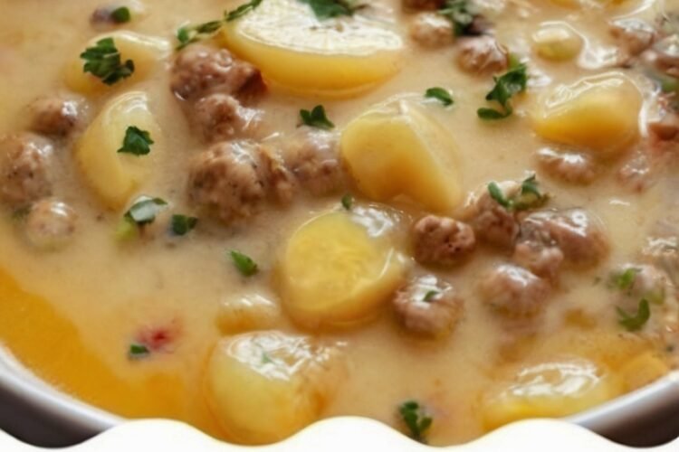 Creamy cheesy potato and beef soup made with tender diced potatoes, seasoned ground beef, onions, garlic, and a rich beef broth. Melted cheddar creates a smooth golden broth, finished with fresh parsley and served hot in a bowl as a cozy, hearty comfort meal.