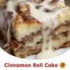 A warm cinnamon roll cake baked in a 9x13-inch pan, featuring a soft golden cake with swirls of buttery cinnamon and brown sugar throughout. A sweet vanilla glaze is drizzled over the top, melting into the warm cake and creating glossy, gooey pockets of cinnamon sweetness.