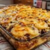 Cheesy hamburger casserole layered with seasoned ground beef, thinly sliced russet potatoes, and shredded cheddar cheese, covered in a creamy cheddar sauce. Baked until the potatoes are tender and the top is golden, bubbly, and melted, creating a hearty and comforting family dinner.
