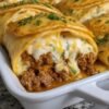 Cheeseburger pockets made with flaky crescent roll dough filled with seasoned ground beef, sautéed onions, ketchup, mustard, Worcestershire sauce, and melted cheddar cheese. The pockets are baked until golden brown and crisp, creating a warm, cheesy handheld meal that's perfect for a quick family dinner or snack.