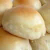 Soft, fluffy homemade dinner rolls baked until golden brown and glossy, with tender cloud-like centers. The warm rolls are brushed with melted butter and arranged together in a baking dish or basket, making a comforting side dish perfect for dinner, soup, or serving with butter and honey.