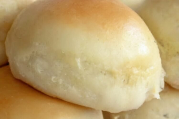 Soft, fluffy homemade dinner rolls baked until golden brown and glossy, with tender cloud-like centers. The warm rolls are brushed with melted butter and arranged together in a baking dish or basket, making a comforting side dish perfect for dinner, soup, or serving with butter and honey.