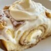 Banana Bread Cinnamon Rolls made with soft banana-infused dough, a buttery cinnamon-brown sugar filling, and creamy cream cheese frosting. The rolls are baked until golden and fluffy, then generously frosted while warm so the frosting melts into the cinnamon swirls, creating an indulgent breakfast or dessert.
