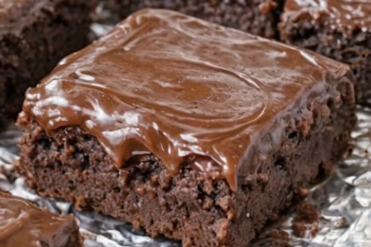 Fudgy chocolate brownies made with chocolate cake mix, topped with a thick, glossy chocolate frosting. The brownies have slightly crisp edges, a crackly top, and a rich, soft center, cut into neat squares and served as an indulgent homemade dessert.