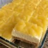 No-bake pineapple cream cheese dessert with a buttery graham cracker crust, a smooth and creamy sweetened cream cheese layer, and a glossy topping of crushed pineapple. The chilled dessert is cut into neat squares and served as a light, tropical, nostalgic treat.