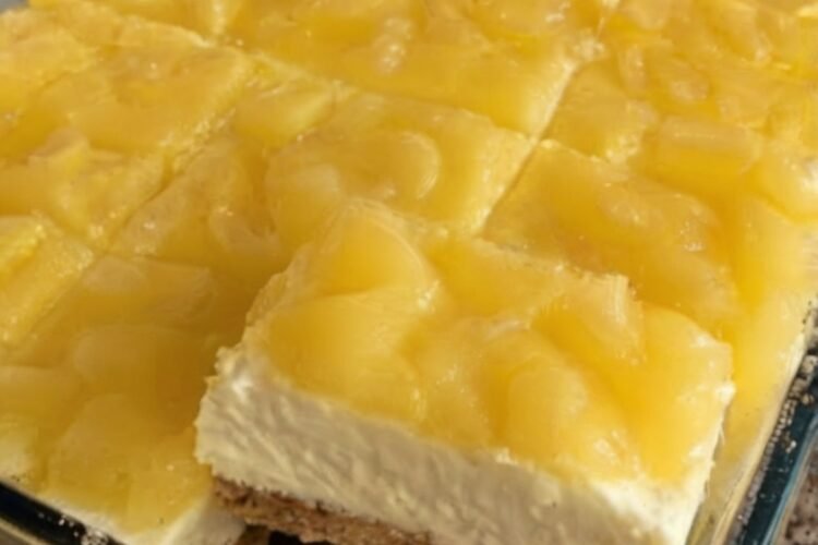 No-bake pineapple cream cheese dessert with a buttery graham cracker crust, a smooth and creamy sweetened cream cheese layer, and a glossy topping of crushed pineapple. The chilled dessert is cut into neat squares and served as a light, tropical, nostalgic treat.