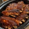 Slow cooker baby back ribs coated in a sweet, tangy barbecue sauce with brown sugar, apple cider vinegar, garlic, and smoked paprika. The ribs are fall-apart tender with a glossy, sticky caramelized glaze and slightly charred edges, served as a classic comfort-food barbecue dinner.