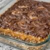Four-ingredient layered chocolate peanut butter dessert bars with a buttery graham cracker crust, a rich caramel-like condensed milk layer, and a glossy chocolate-peanut butter topping swirled into a marbled pattern. The chilled bars are cut into squares, creating a rich, sweet-and-salty homemade dessert.
