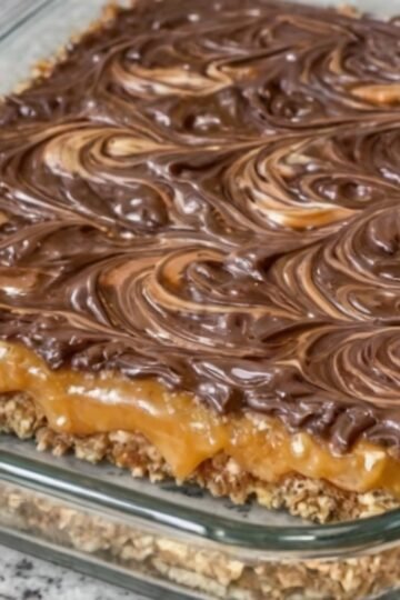 Four-ingredient layered chocolate peanut butter dessert bars with a buttery graham cracker crust, a rich caramel-like condensed milk layer, and a glossy chocolate-peanut butter topping swirled into a marbled pattern. The chilled bars are cut into squares, creating a rich, sweet-and-salty homemade dessert.