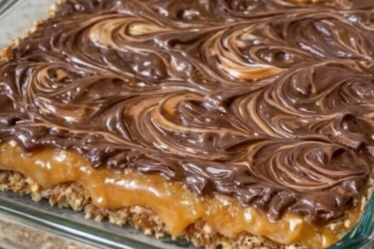 Four-ingredient layered chocolate peanut butter dessert bars with a buttery graham cracker crust, a rich caramel-like condensed milk layer, and a glossy chocolate-peanut butter topping swirled into a marbled pattern. The chilled bars are cut into squares, creating a rich, sweet-and-salty homemade dessert.