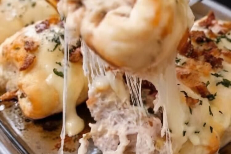 Golden-brown stuffed breadstick bombs filled with creamy chicken Alfredo, crispy bacon, melted mozzarella, and Parmesan cheese. The soft baked dough has a buttery garlic-Parmesan topping, with the cheesy filling visible inside. Served warm on a parchment-lined baking sheet as an irresistible appetizer or comfort-food snack.