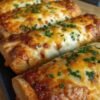 Golden-brown Cheesy Taco Sticks made with seasoned ground beef, melted mozzarella and cheddar cheese wrapped inside soft pizza dough. The sticks are brushed with garlic butter and dried parsley, baked until crisp and golden, and served warm with salsa, sour cream, and guacamole for dipping.