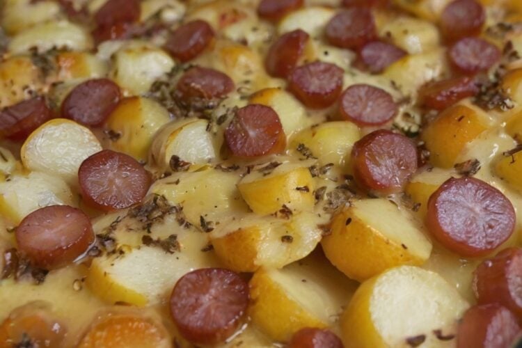 A hearty Smoked Sausage and Potato Bake featuring sliced smoked sausage, tender golden Yukon gold potatoes, and diced green and yellow bell peppers roasted together with butter, olive oil, oregano, and basil. The sausage and potatoes have lightly caramelized edges and are served hot in a rustic baking dish for a cozy, one-pan family dinne