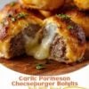 Golden Garlic Parmesan Cheeseburger Bombs baked until crisp and buttery, made with flaky biscuit dough stuffed with seasoned ground beef and gooey melted mozzarella cheese. One bomb is cut open to reveal the stretchy cheese pull and savory beef filling, brushed with garlic butter, sprinkled with Parmesan and fresh parsley, and served with warm marinara dipping sauce on a rustic wooden board. Photographed in warm natural light for an irresistible homemade appetizer or family dinner.