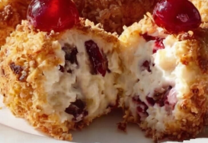 A festive platter of bite-sized cherry coconut treats, with creamy white centers speckled with cherries, coated in toasted golden coconut, and topped with bright red maraschino cherries.