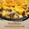 A hearty cheeseburger casserole topped with crispy golden French fries and melted cheddar cheese, with creamy seasoned ground beef layered underneath and served hot from a baking dish.