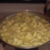 A large pot filled with creamy chicken and dumplings, featuring tender homemade dumplings simmering in a rich, savory broth on a stovetop.