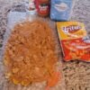 Sweet and salty Fritos peanut butter caramel crunch made with crispy corn chips coated in a glossy mixture of peanut butter, corn syrup, and sugar. The coating sets into a chewy, caramel-like layer around the crunchy Fritos, creating an irresistible homemade snack treat.