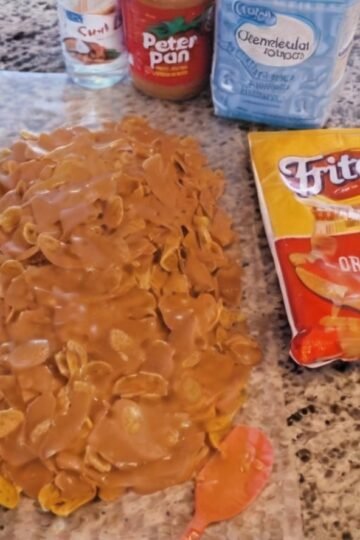 Sweet and salty Fritos peanut butter caramel crunch made with crispy corn chips coated in a glossy mixture of peanut butter, corn syrup, and sugar. The coating sets into a chewy, caramel-like layer around the crunchy Fritos, creating an irresistible homemade snack treat.