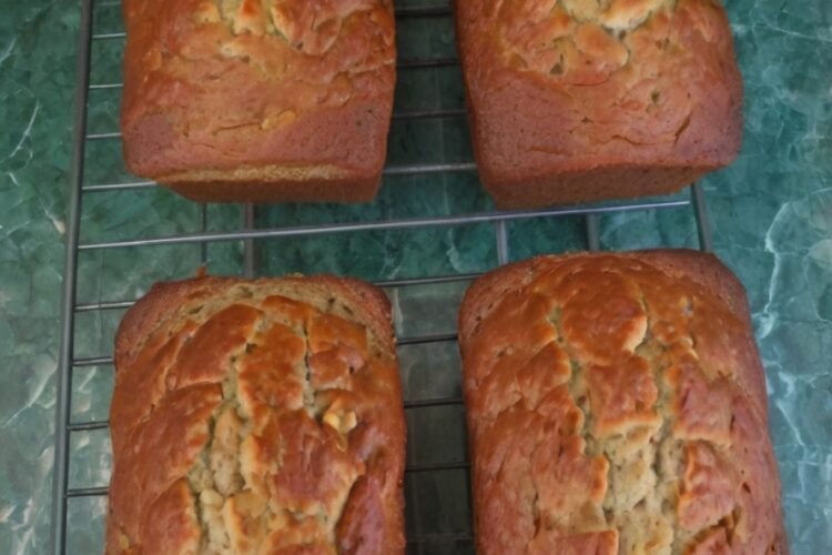 Moist homemade banana nut bread loaf, golden brown on top and filled with ripe banana flavor and chopped walnuts or pecans, sliced and ready to serve.
