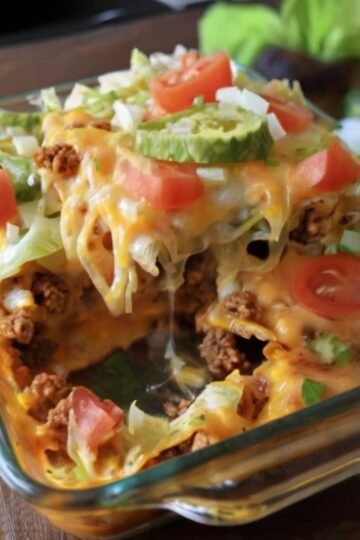 Cheesy taco bake made with golden crescent roll dough, seasoned ground beef, melted cheddar cheese, shredded lettuce, and diced tomatoes.