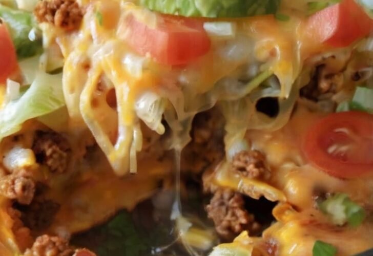 Cheesy taco bake made with golden crescent roll dough, seasoned ground beef, melted cheddar cheese, shredded lettuce, and diced tomatoes.