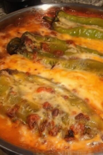Baked chile rellenos casserole topped with melted golden cheese, featuring roasted poblano peppers nestled in a creamy egg-and-cheese mixture inside a round baking dish.