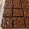 Homemade chocolate crunch bars cut into thick squares, made with crispy rice cereal, creamy peanut butter, and a rich chocolate coating.
