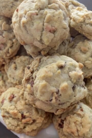 Buttery pecan cookies with a delicate, crumbly shortbread-like texture and toasted chopped pecans throughout. The cookies are lightly golden on the bottoms, pale on top, and dusted generously with powdered sugar for a classic melt-in-your-mouth finish.