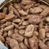 A round decorative tin filled with homemade candied pecan halves coated in a crunchy cinnamon-sugar mixture.